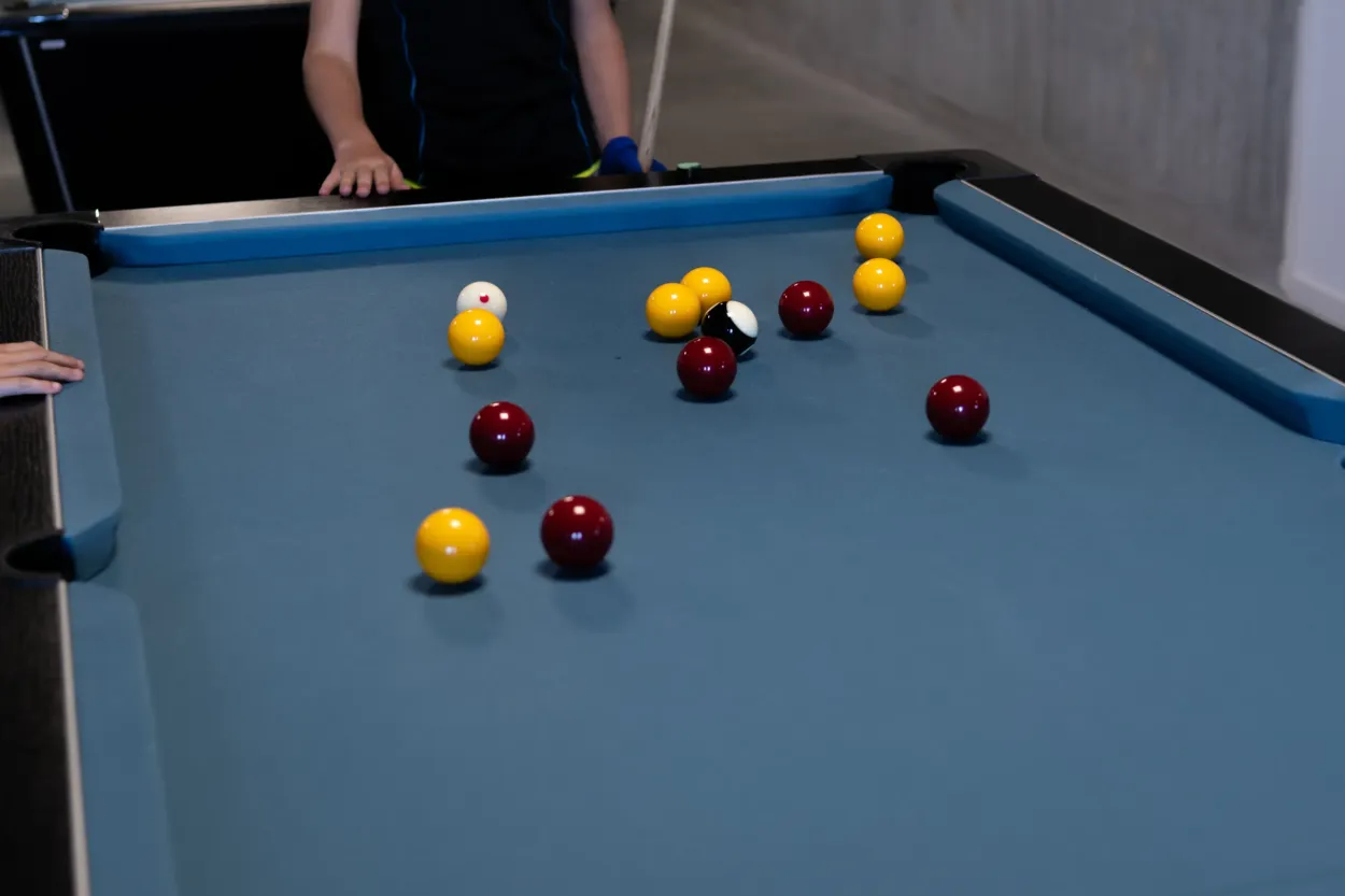 Billes rouges, jaunes et noire sur le tapis bleu d’un billard anglais